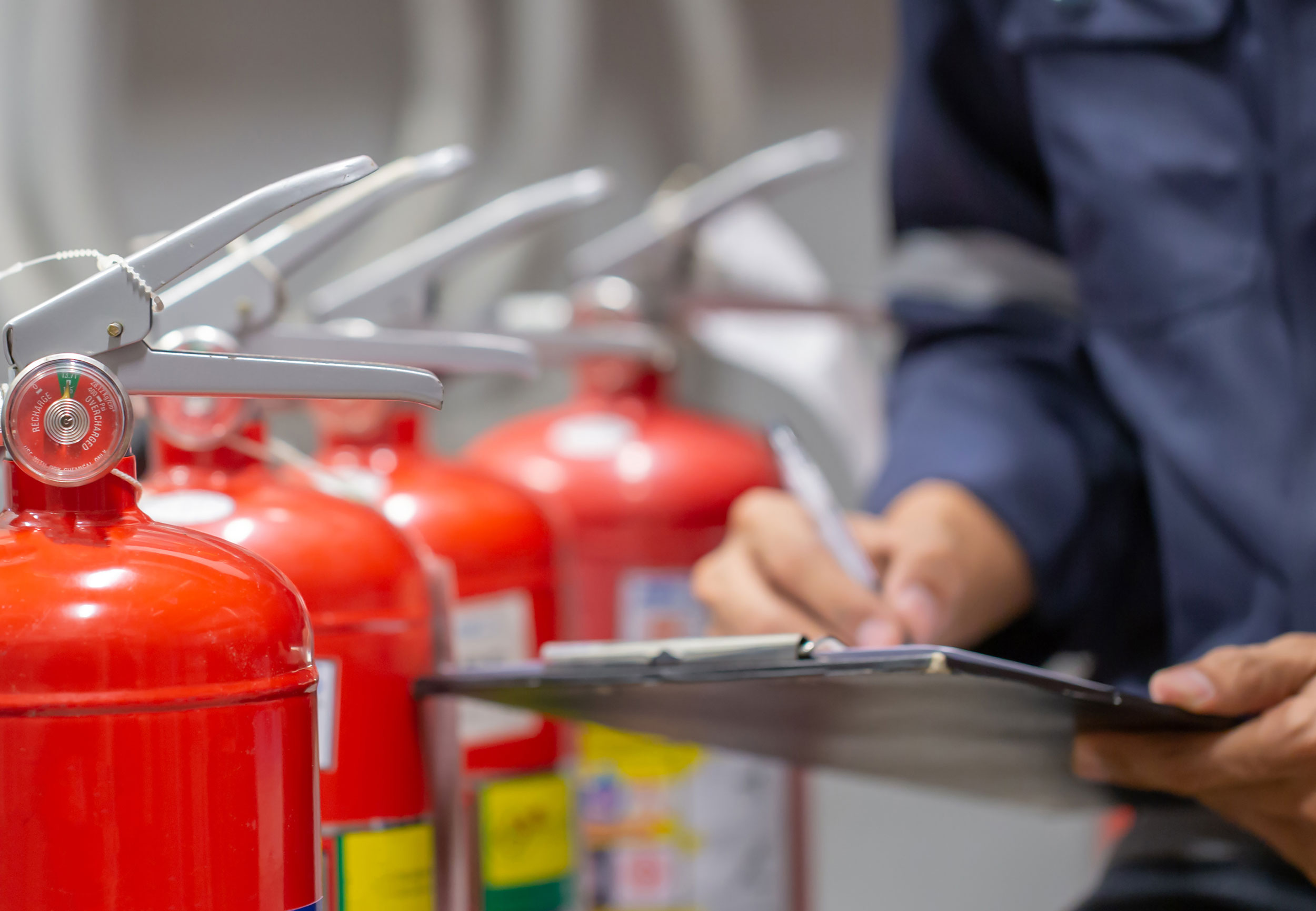 Technician performing a fire extinguisher inspection on red extinguishers in Southeast Missouri