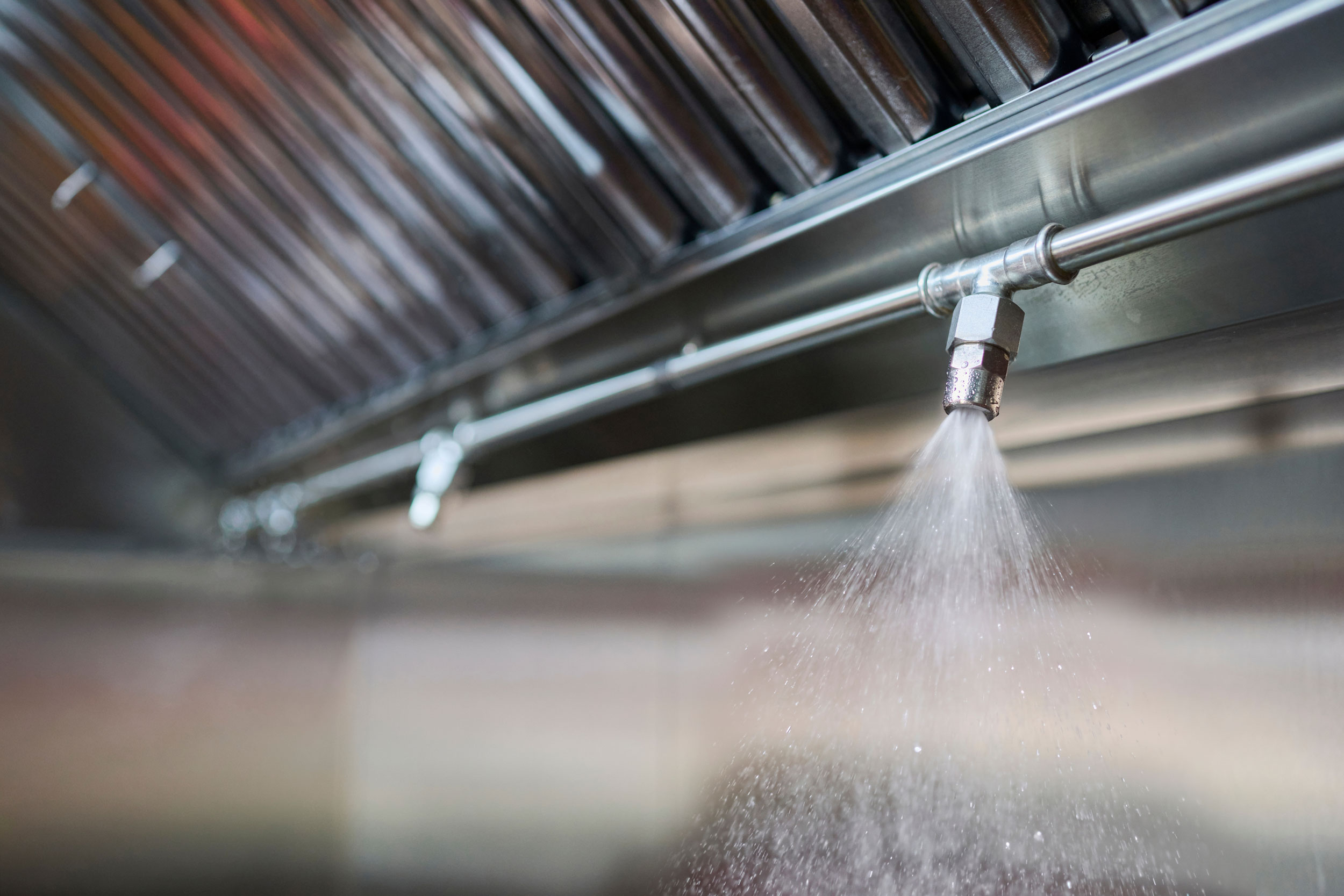 Kitchen hood fire suppression system nozzle discharging under a commercial restaurant hood in Southeast Missouri